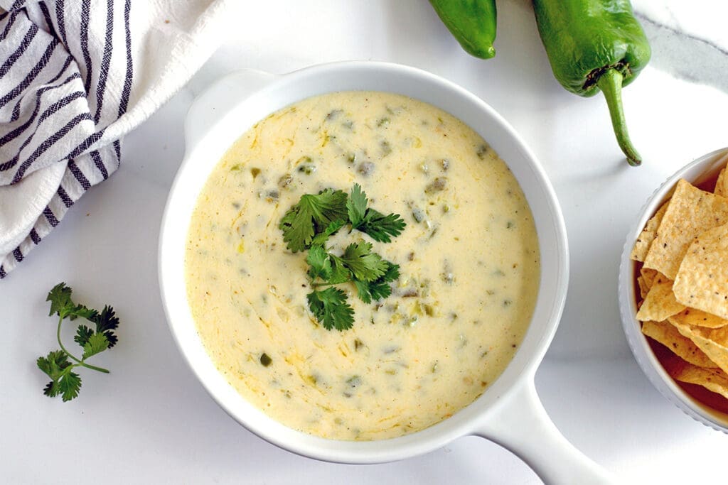 Green Chile Queso with chips and cilantro.