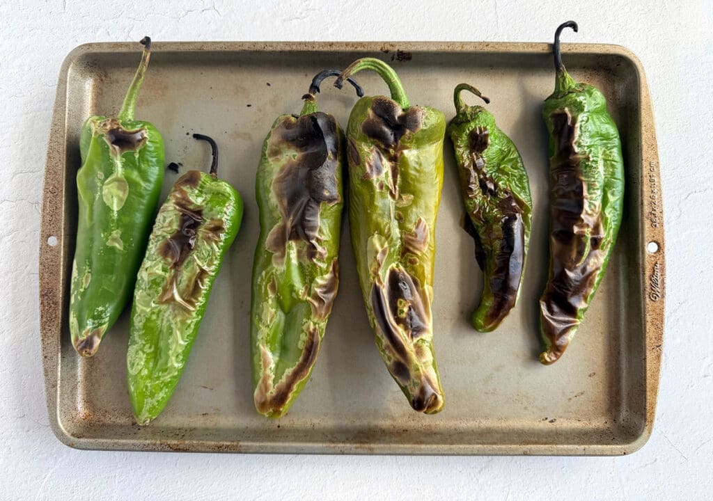 Roasted green chiles on a baking sheet for How to roast peppers article.