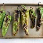 Roasted green chiles on a baking sheet for How to roast peppers article.
