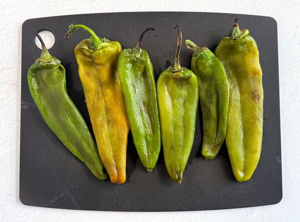 Roasted Hatch Green Chilis on a black cutting board.