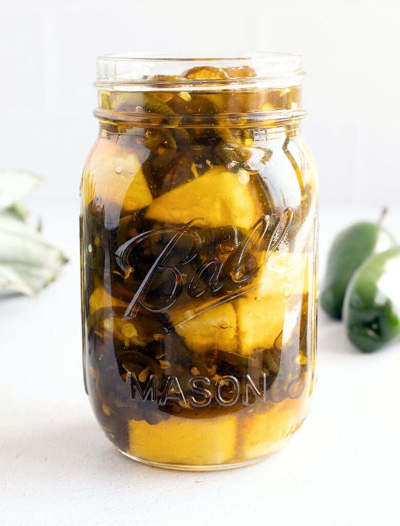 Candied jalapenos with pineapple in a mason jar.