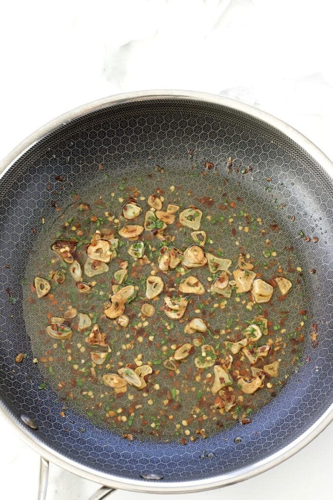 Garlic and red chili peppers cooked in a frying pan.