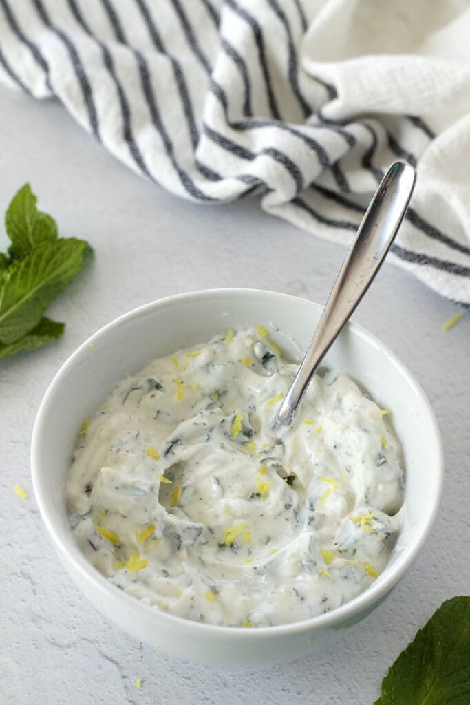 White bowl and serving spoon of lamb sauce.