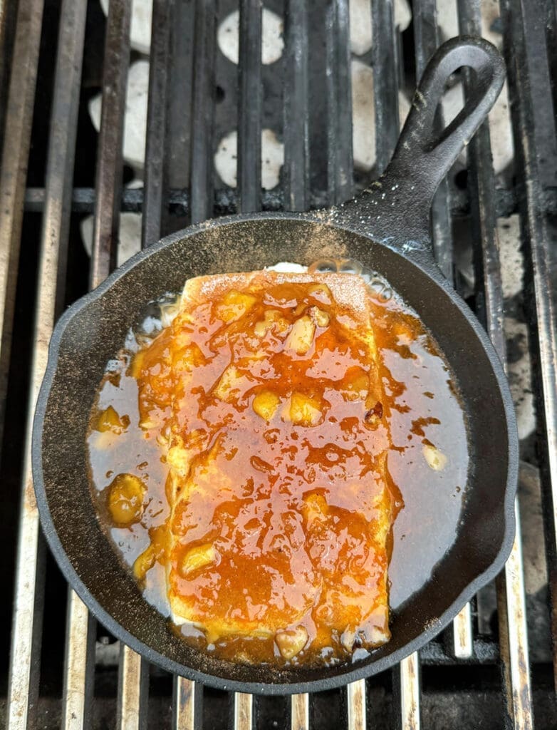 Cream cheese and jam in a small cast iron pan on the grill.