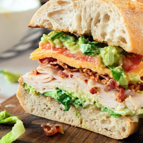 The Turkish Bocado sandwich is cut into half of a cutting board.