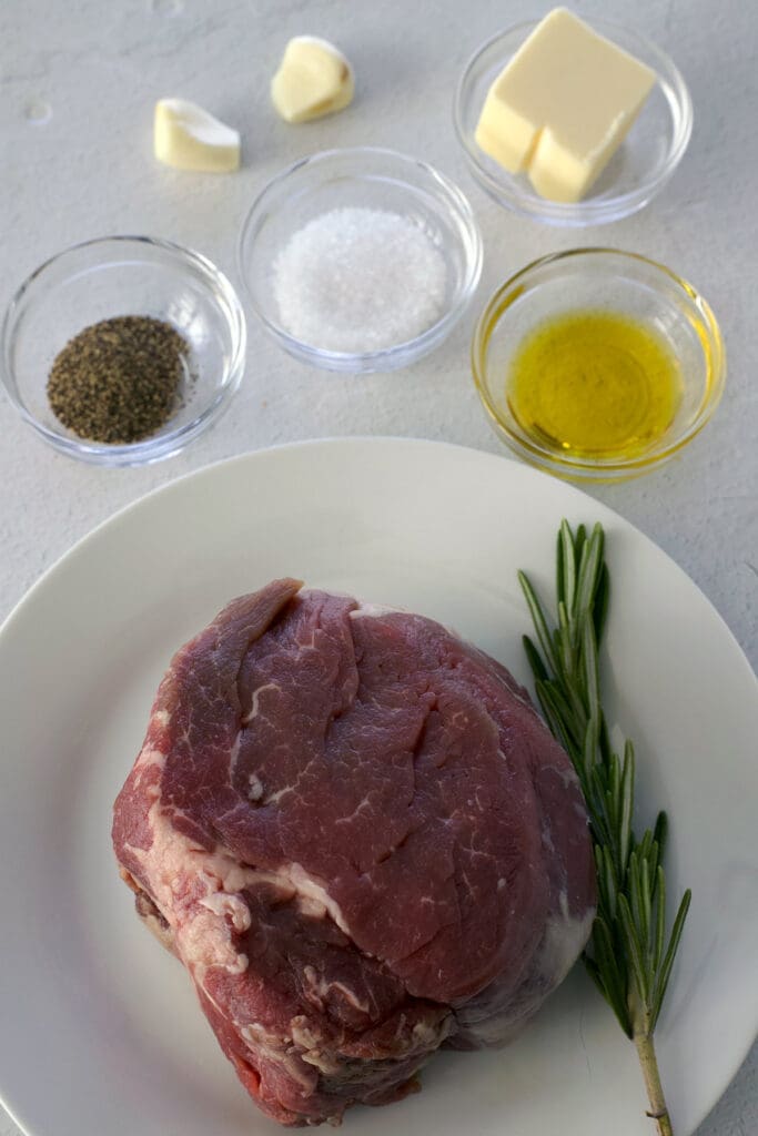 Photo of steak, salt, pepper, oil, garlic and butter in a small bowl.