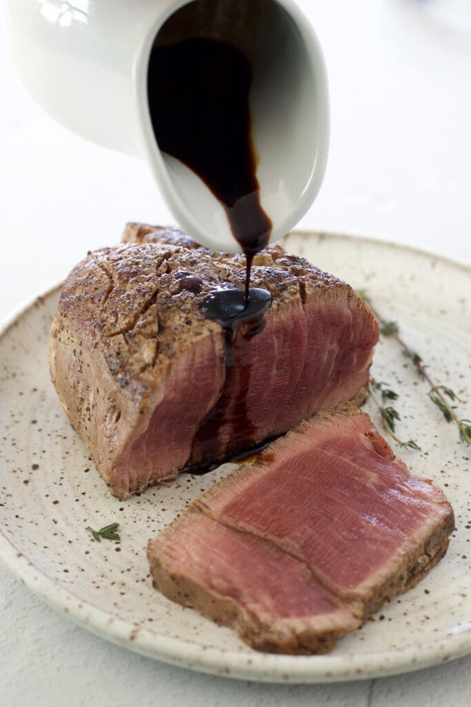 Balsamic glaze is poured over the filet mignon.