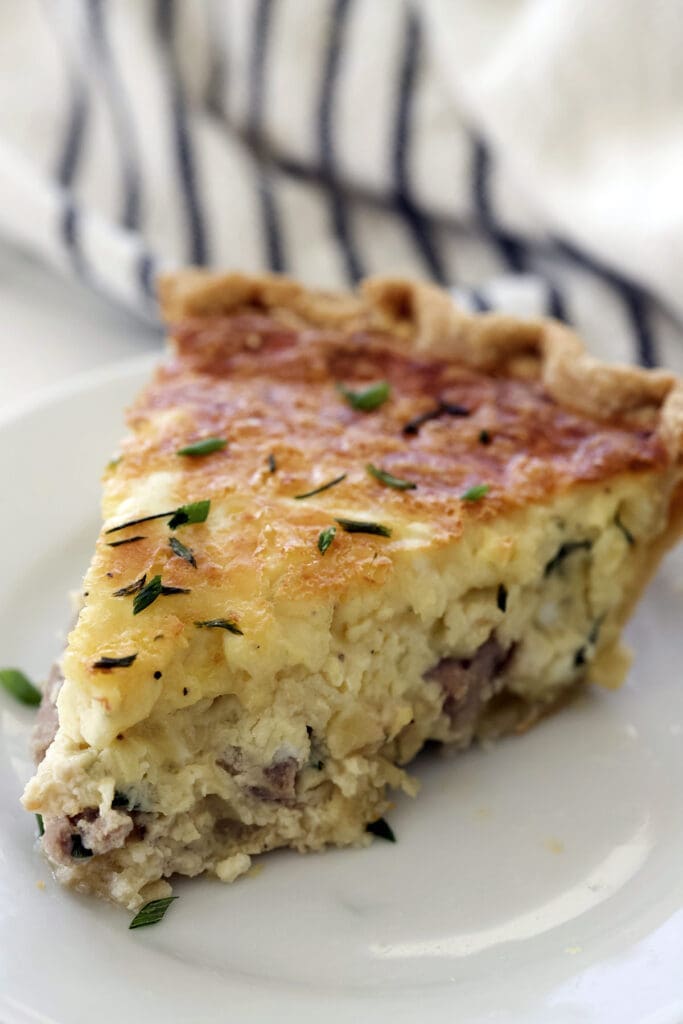 Slice of prime rib quiche on a white plate.