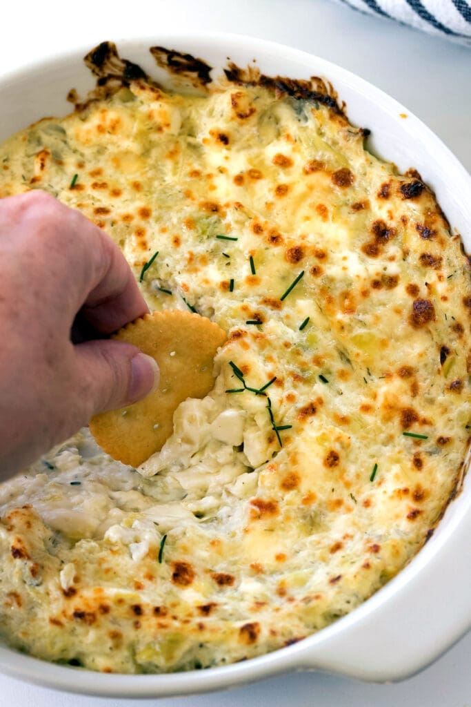 Hand with ritz cracker scooping a hot dip.
