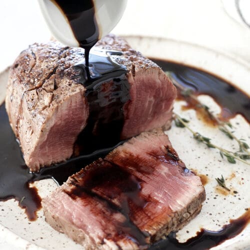 Balsamic glaze is poured over the cut steak.