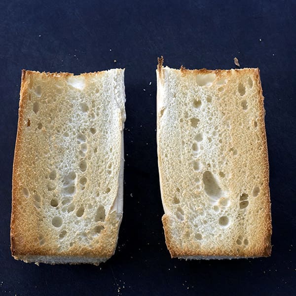 two slices of bread on a black cutting board.