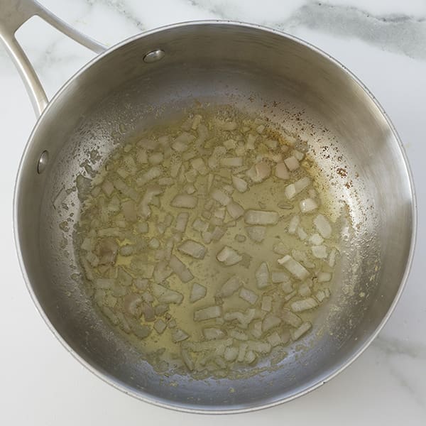 A silver pot with butter and shallots.