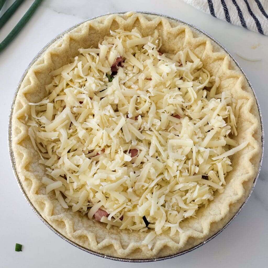 Uncooked eggs and cheese in a pie shell.
