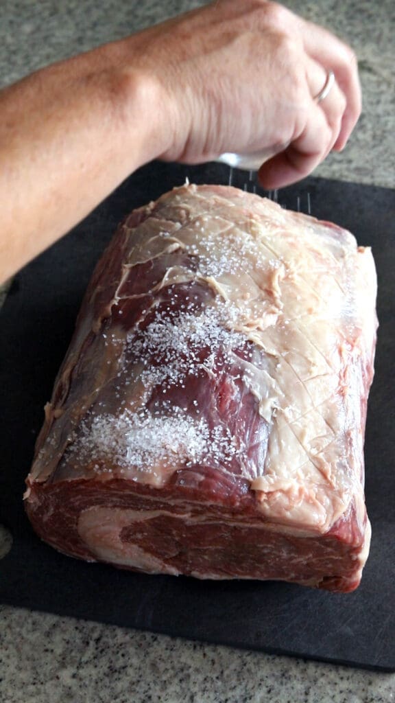 Hand salting a dry brined prime rib roast.