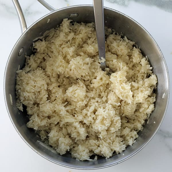 A silver pot with rice and a fork inside.