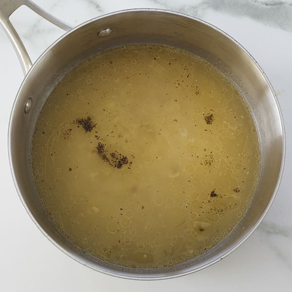 A silver pot with a yellow liquid inside.