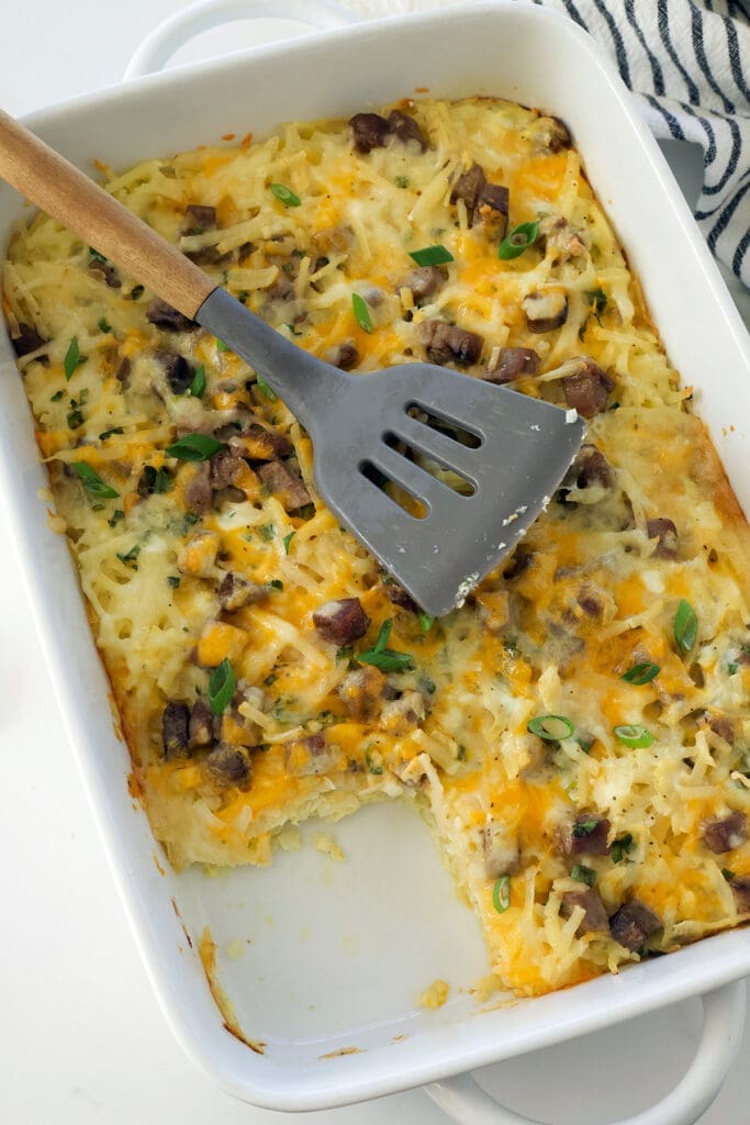 Cut into breakfast casserole with a grey silicon spoon on top.