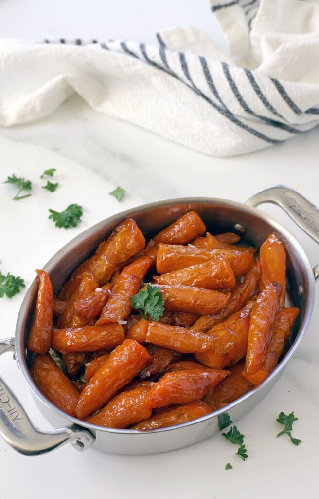 Cooked carrots in a silver baking sheet.