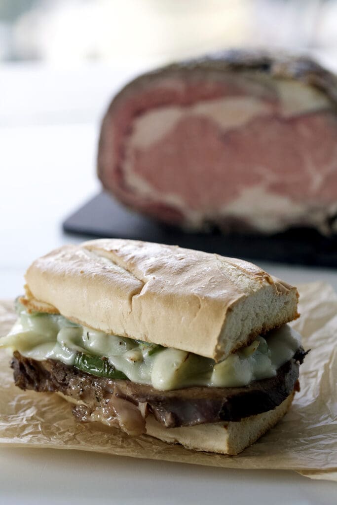 Philly Cheesesteak on parchment next to cut prime rib.