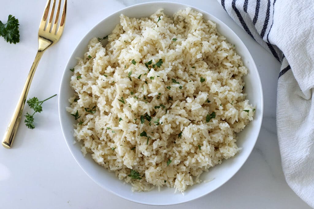 Cheese rice in a white bowl with a golden fork.