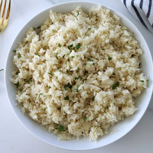 Cheese rice in a white bowl with a golden fork.