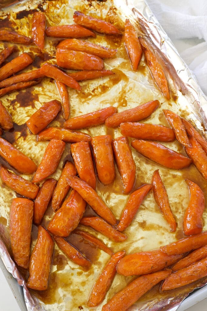 Cooked maple glazed carrots on a baking sheet.