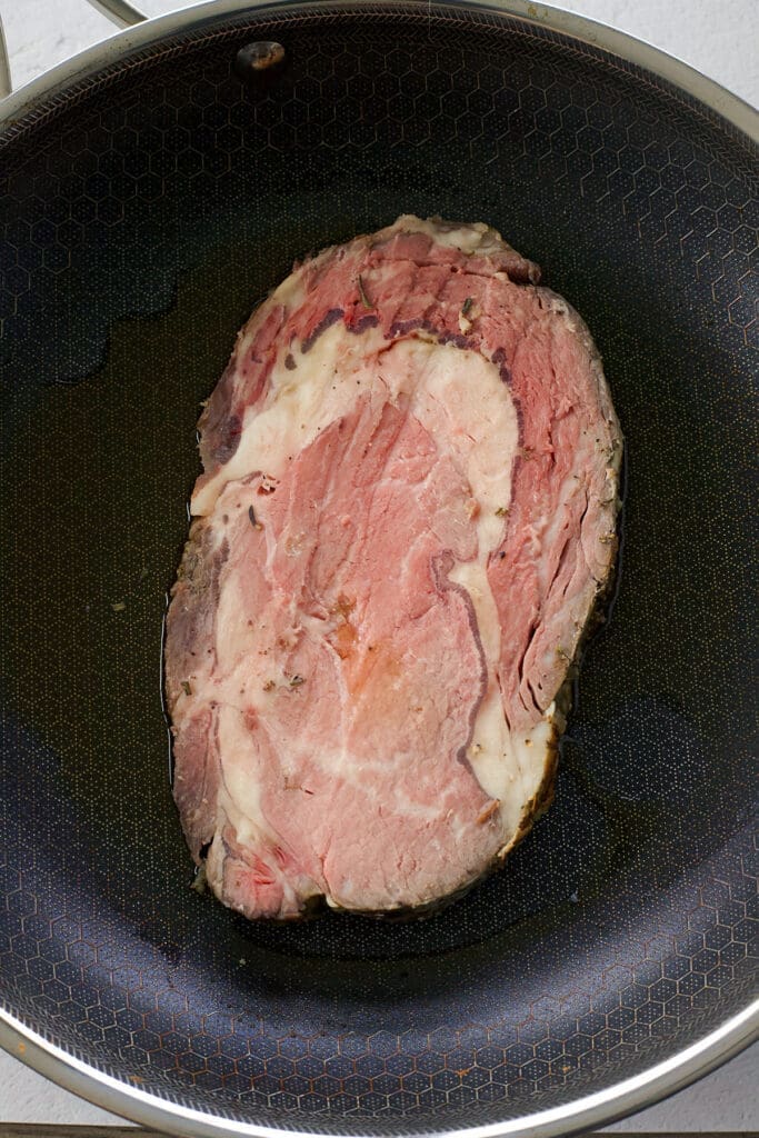 Reheating prime rib steak in a black skillet.