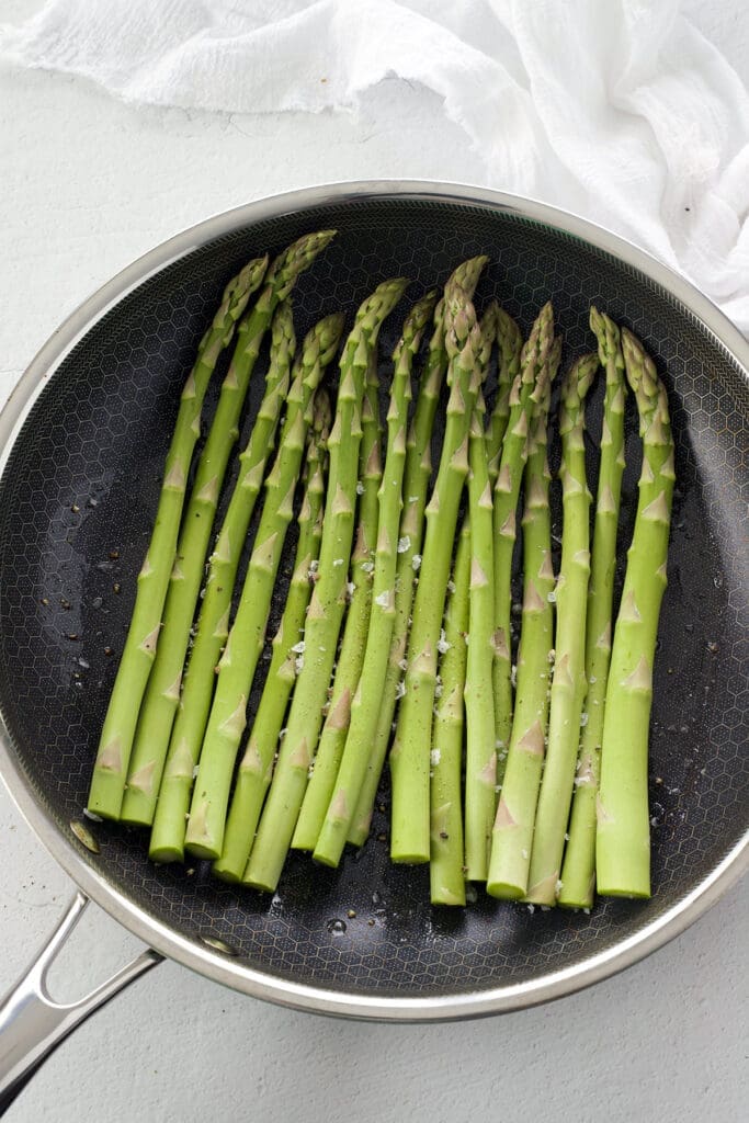 Raw asparagus in a black skillet.