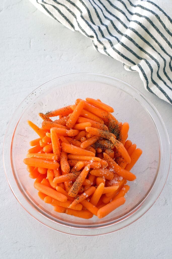 clear bowl full of uncooked baby carrots.