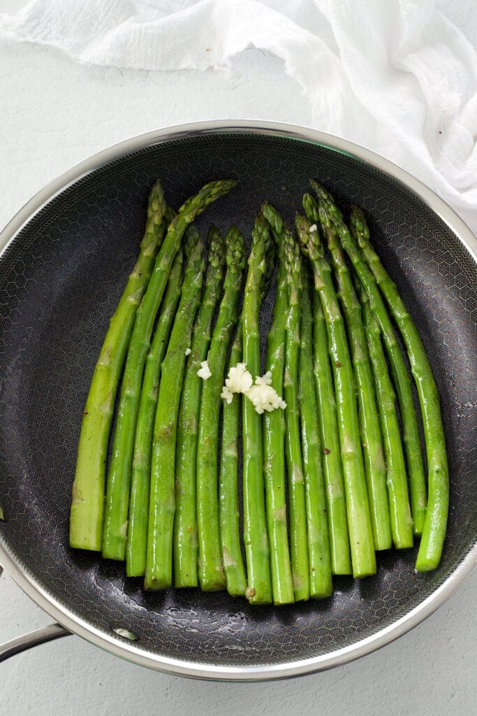 saut&eacute;ed asparagus and garlic in a black skillet.