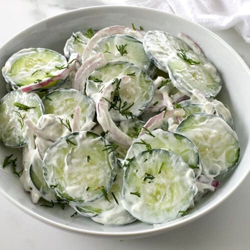 A white bowl filled with creamy cucumber salad.