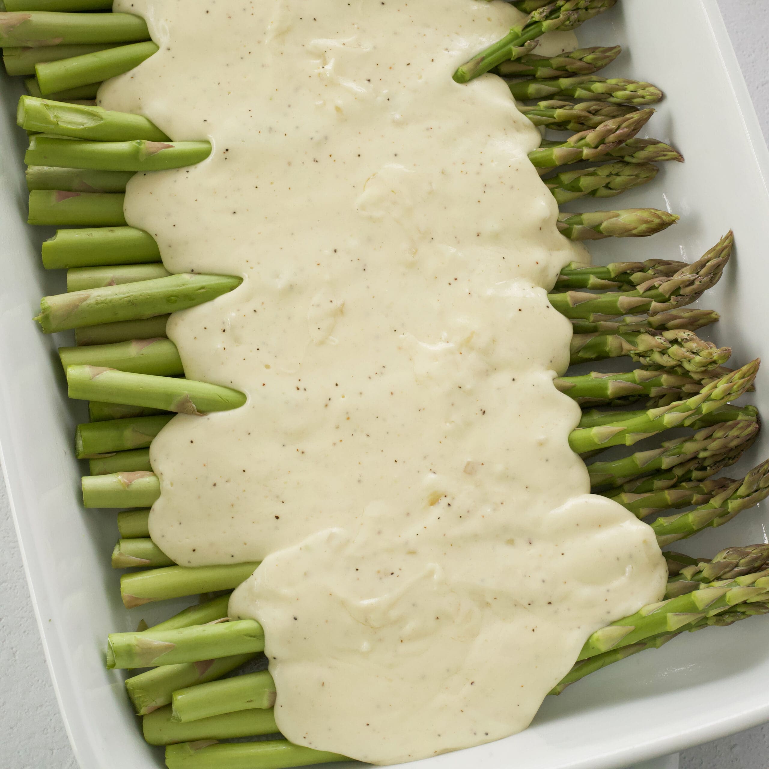 Cheese sauce onto of uncooked asparagus.