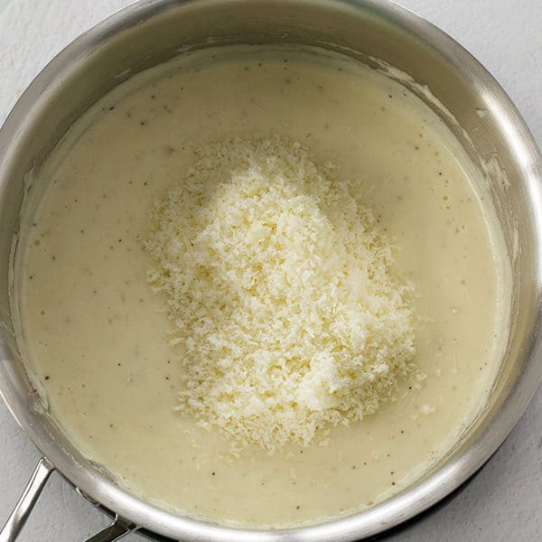 Silver sauce pan full of cheese sauce.