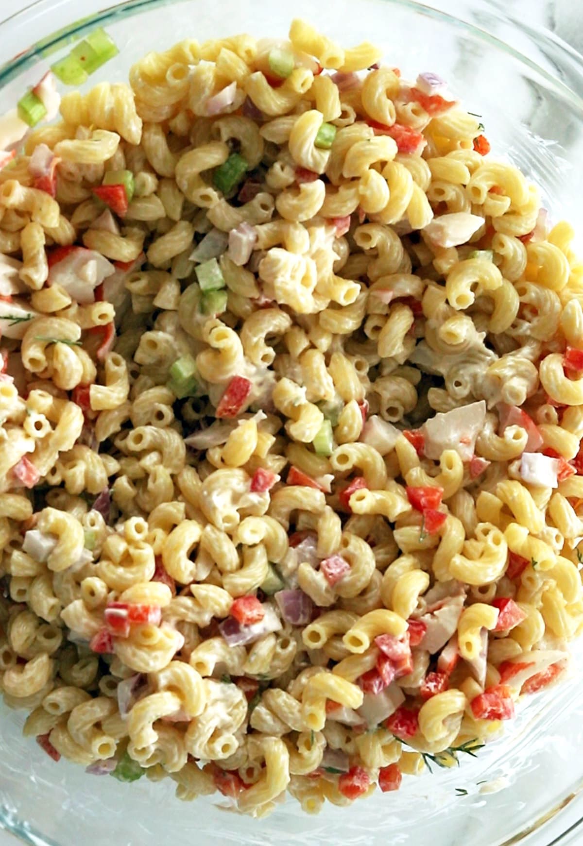 Crab pasta salad in a transparent mixing bowl.