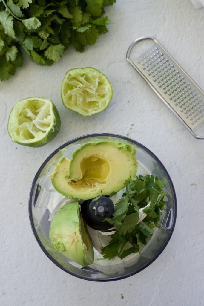 Avocado and cilantro in a small blender.