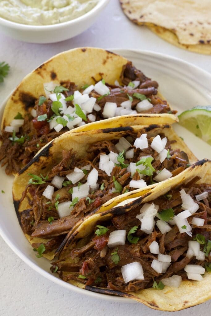 3 meat filled tortillas on a white plate.