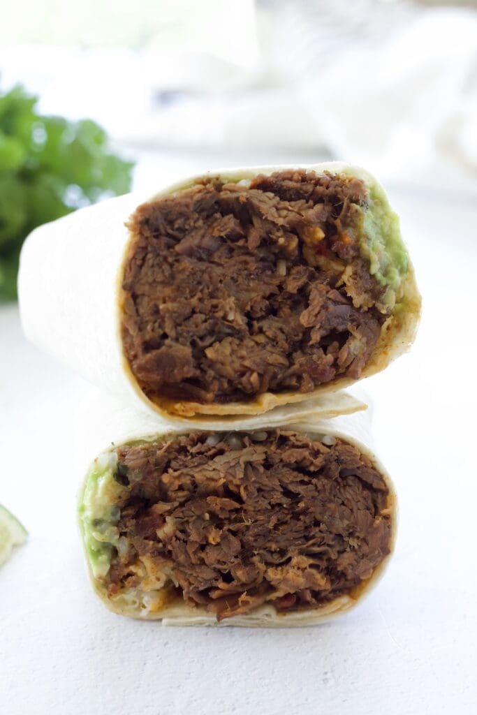 Two pieces of shredded beef burrito stacked on top of each other.
