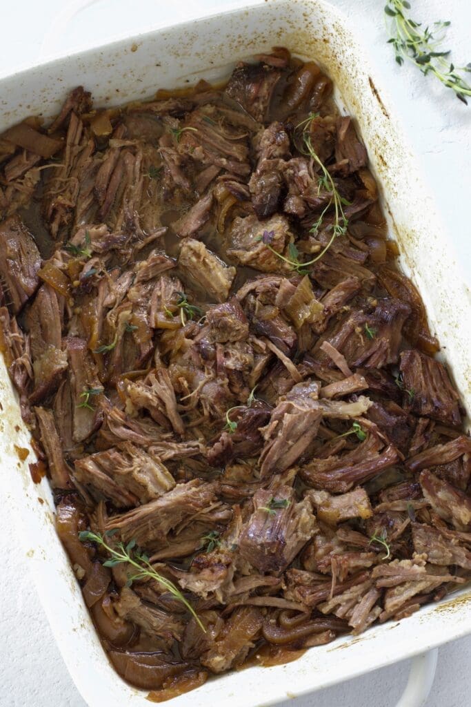 Oven roasted chuck roast in a white baking dish.