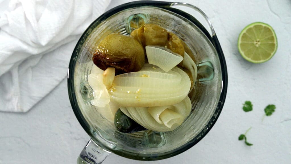 Blender full of vegetables for green salsa.