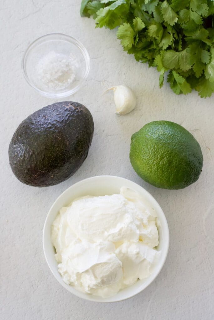 Bowl of sour cream with cilantro and lime.