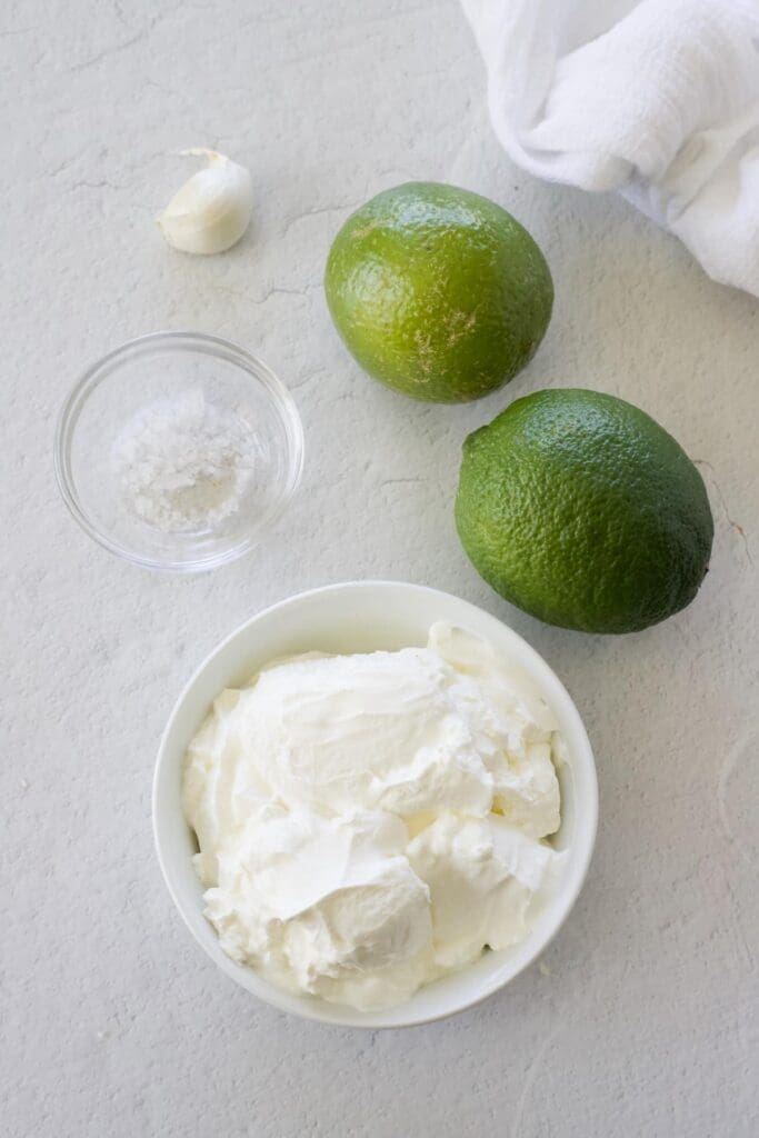 Bowl of sour cream, limes, garlic and salt.