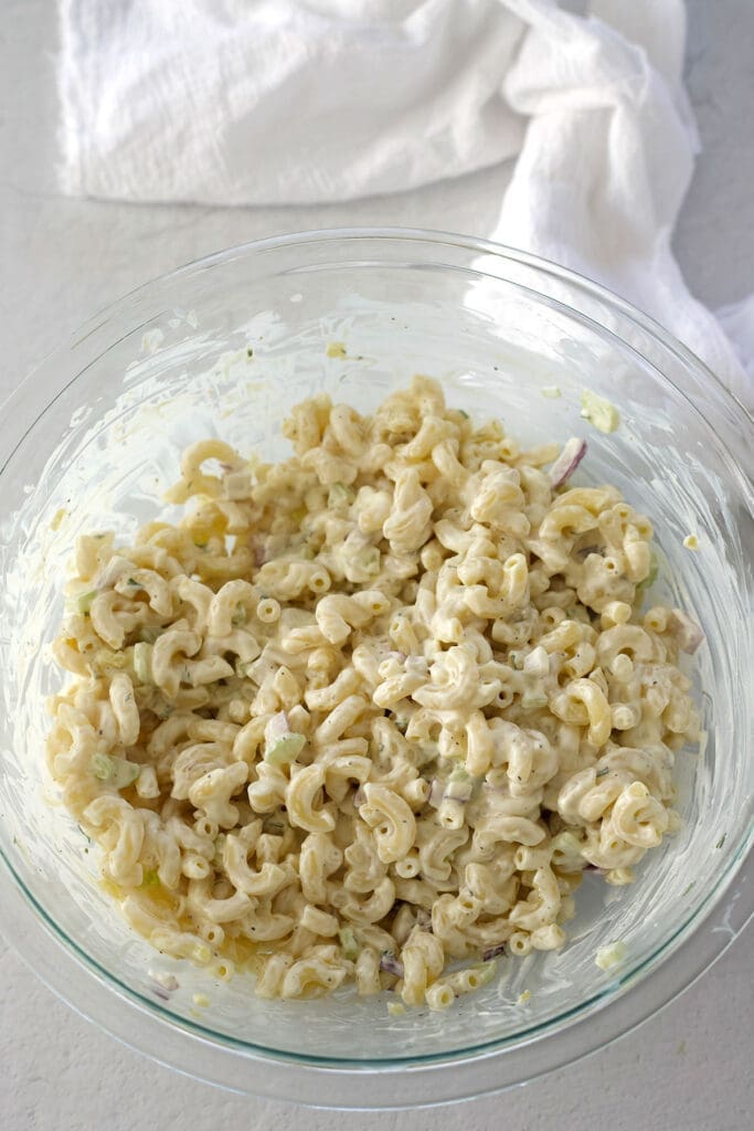 Freshly mixed macaroni salad in a clear bowl.