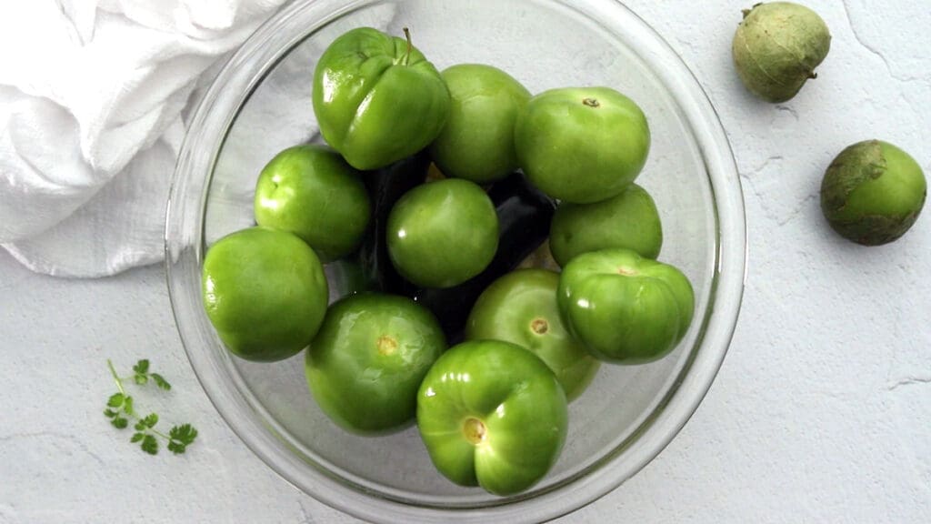 raw tomatillos in a clear bowl.