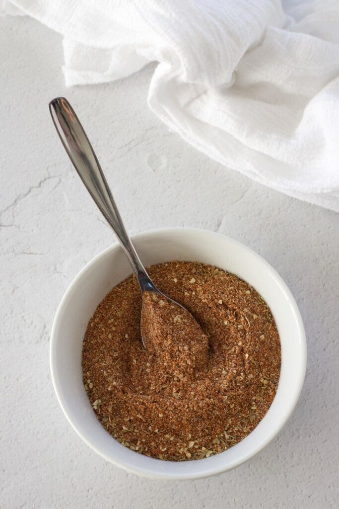 Blackening spice mix in a white bowl with a spoon.