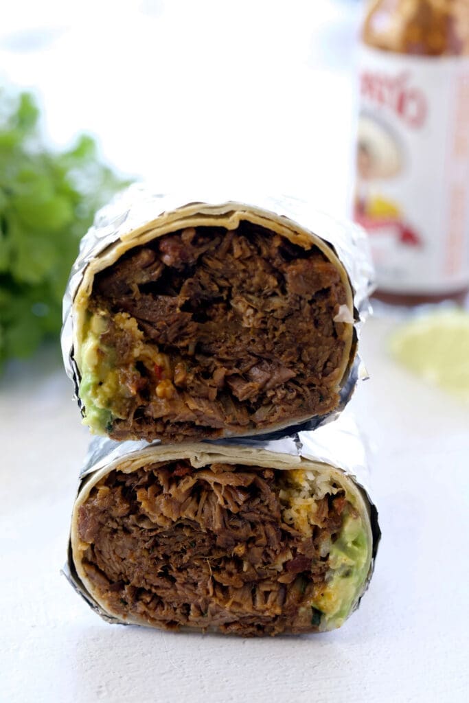 shredded beef burrito cut in half and stacked on top of each other.