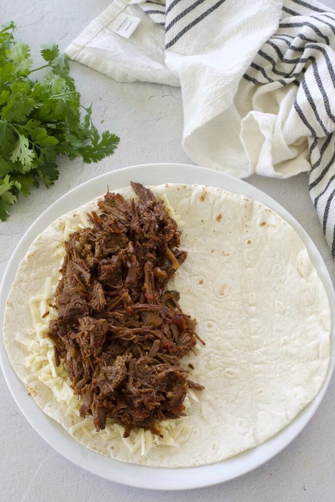 Flour tortilla filled with beef and cheese on one side.