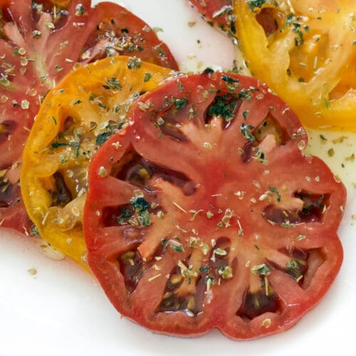 Sliced produce topped with dried herbs.